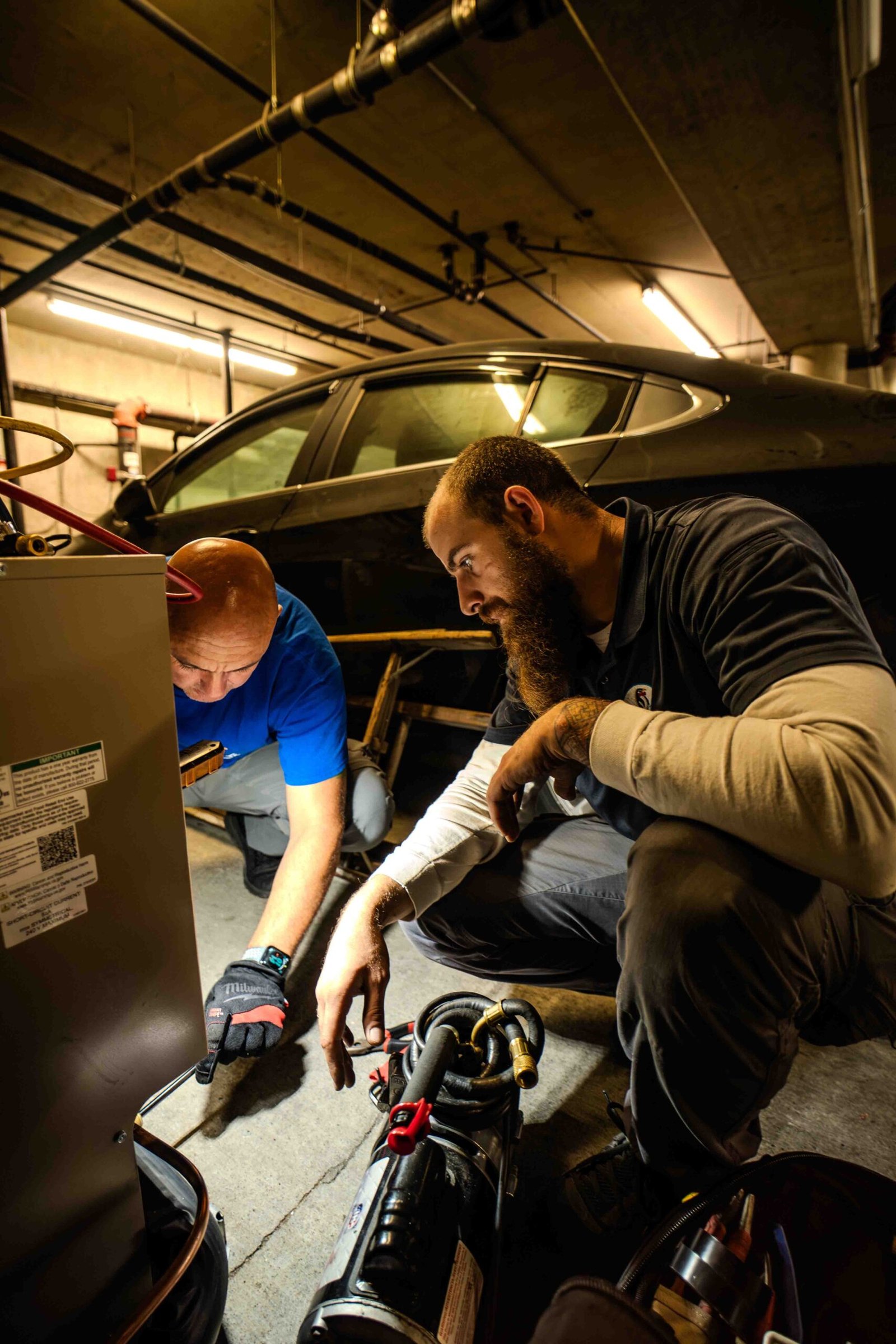 Two Mr. Fridge Austin technicians repairing a compressor during a new walk-in cooler installation.