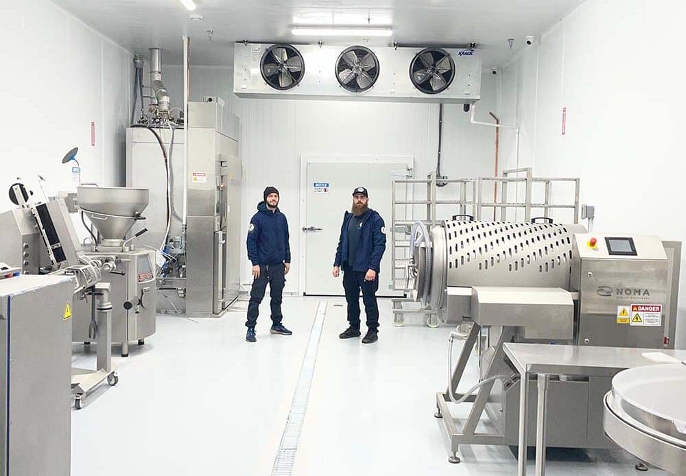 Two Mr. Fridge technicians in a refrigerated food-processing room