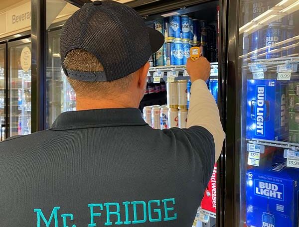 Mr. Fridge technician inspecting a glass-door beverage cooler