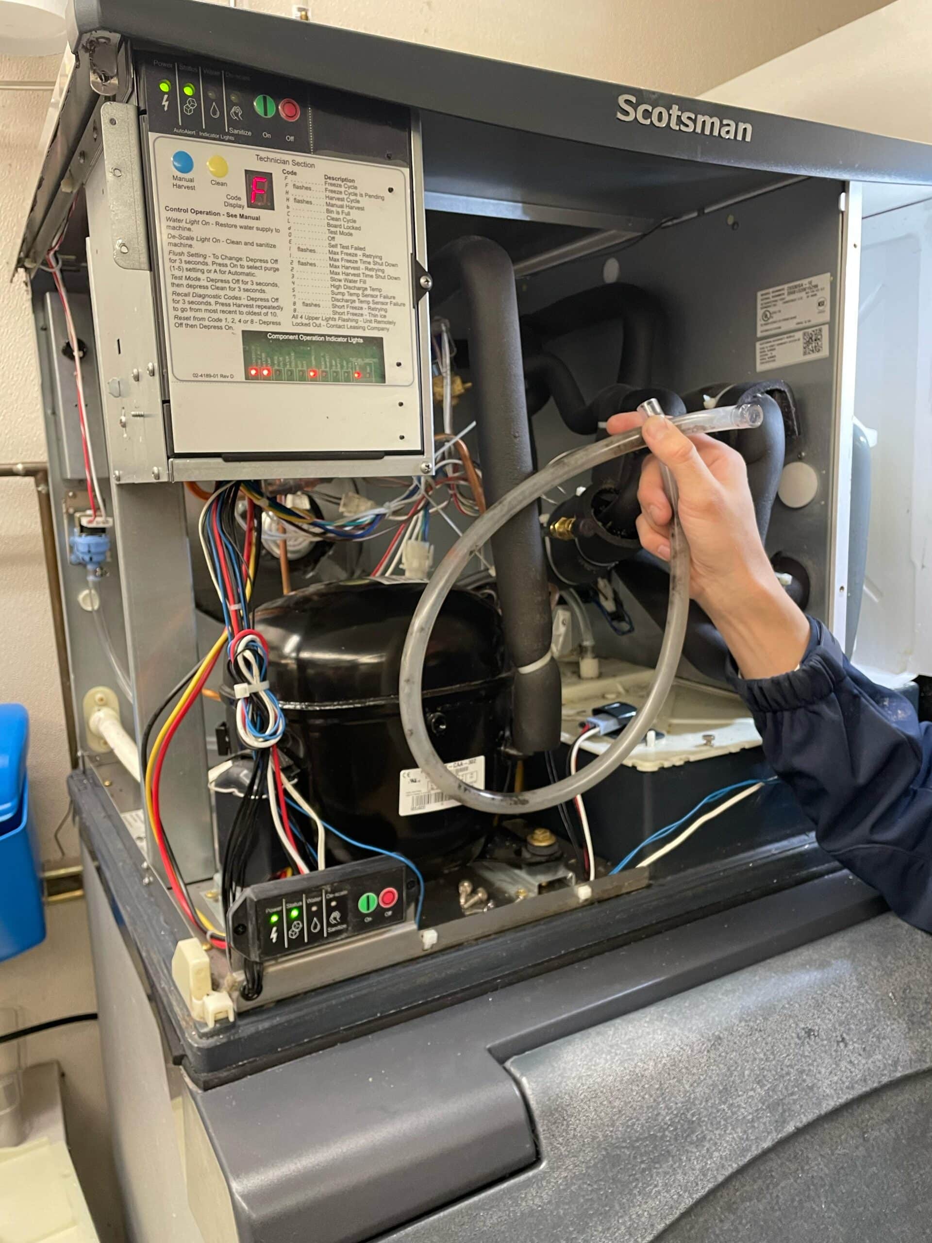 Technician inspecting the open service compartment of a Scotsman ice machine