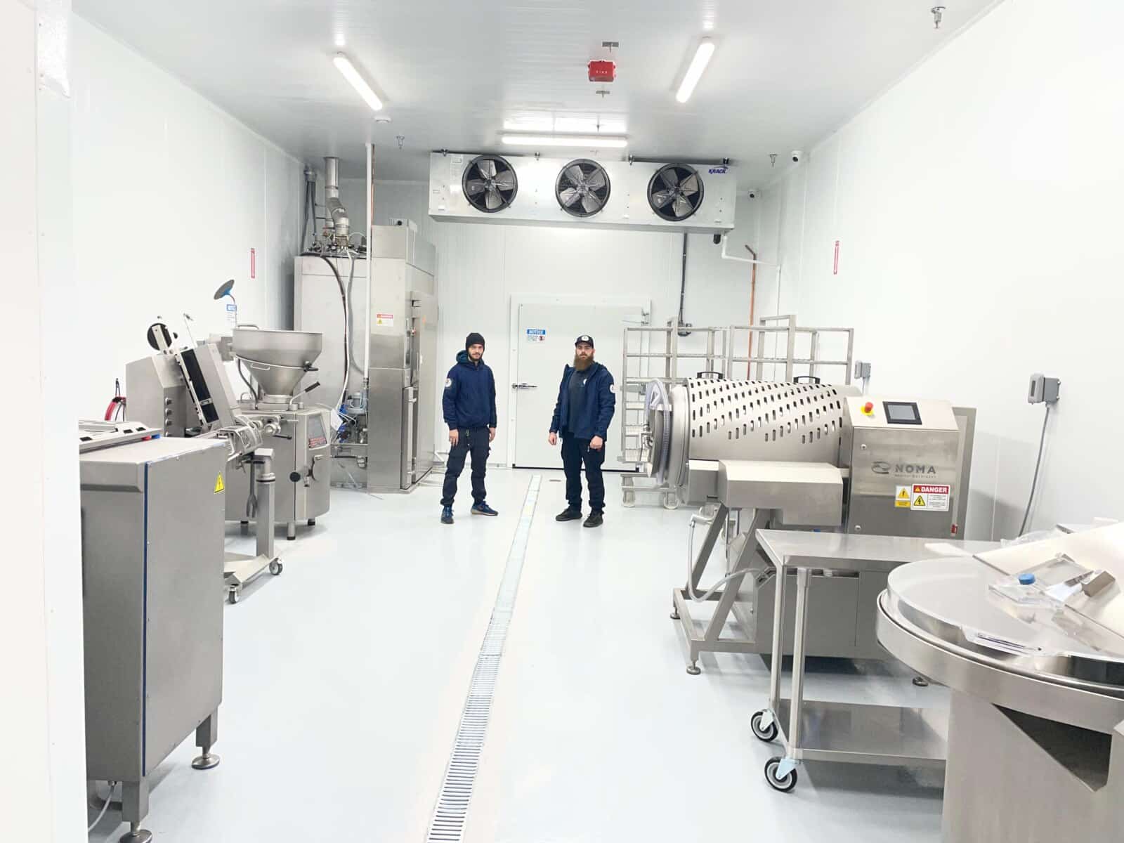 Two Mr. Fridge technicians inside a refrigerated food-processing room