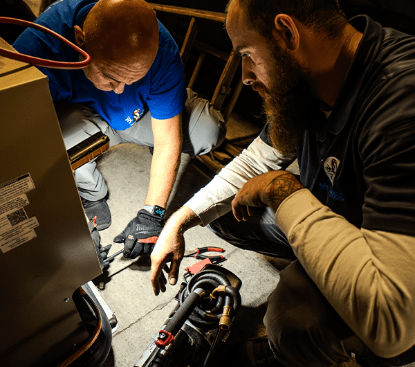 Two technicians working together on refrigeration compressor equipment